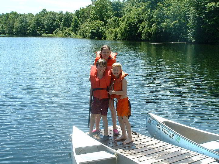 kids wearing life jackets while standing on dock